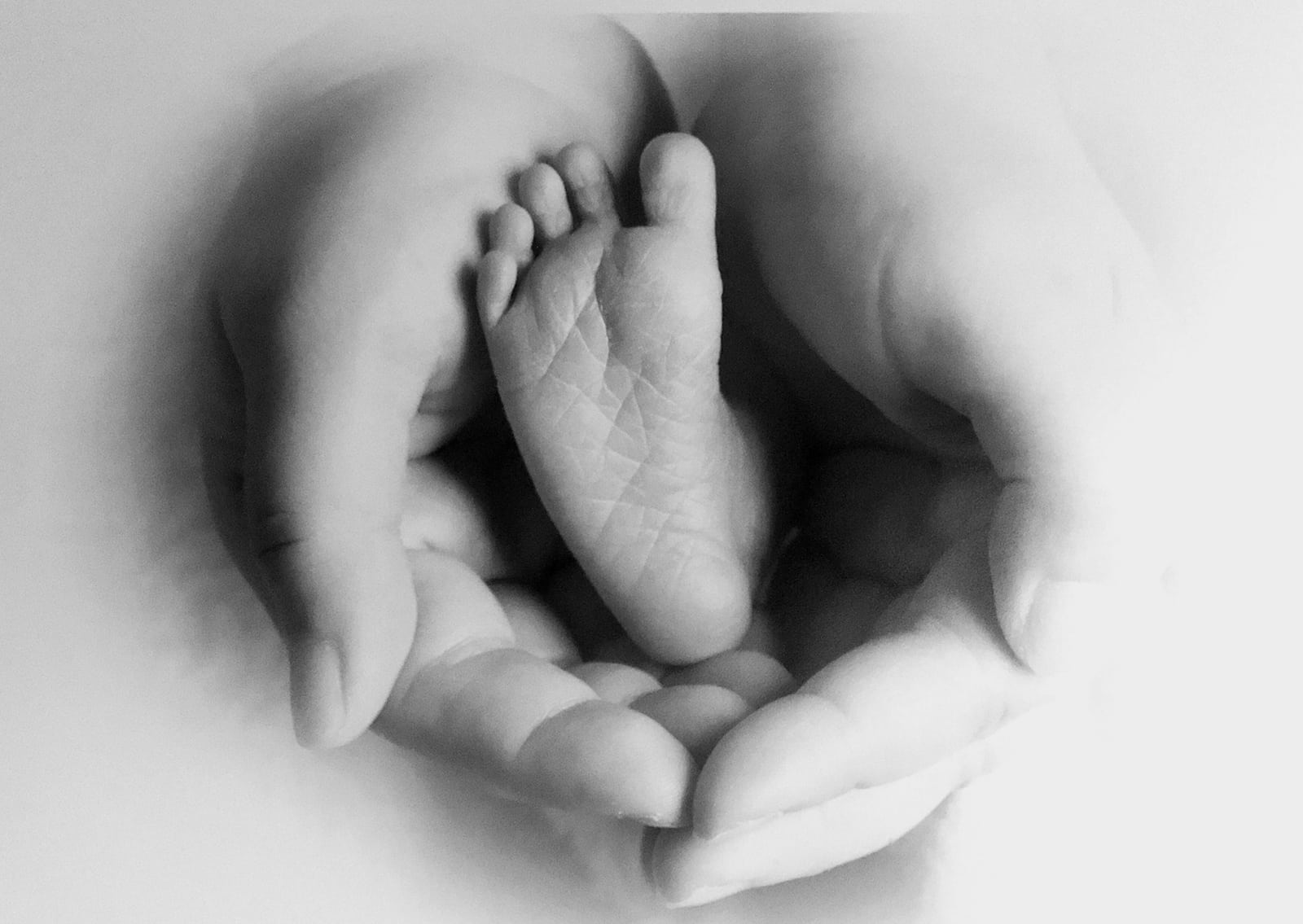 Newborn baby’s foot embraced by mother’s hands, symbolizing overcoming irrational fear of C-section and gaining birth confidence.