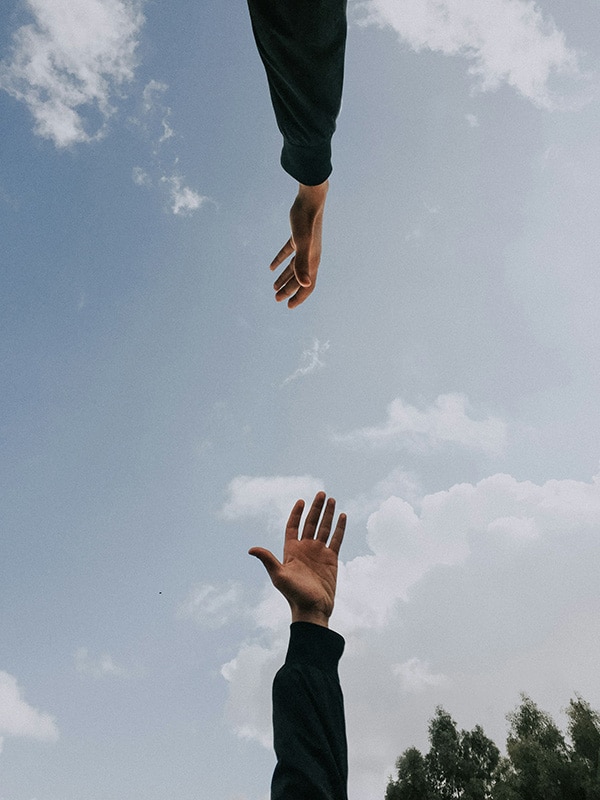 Two hands reaching out to each other, symbolizing support and connection, offering help for tomophobia treatment consultation.